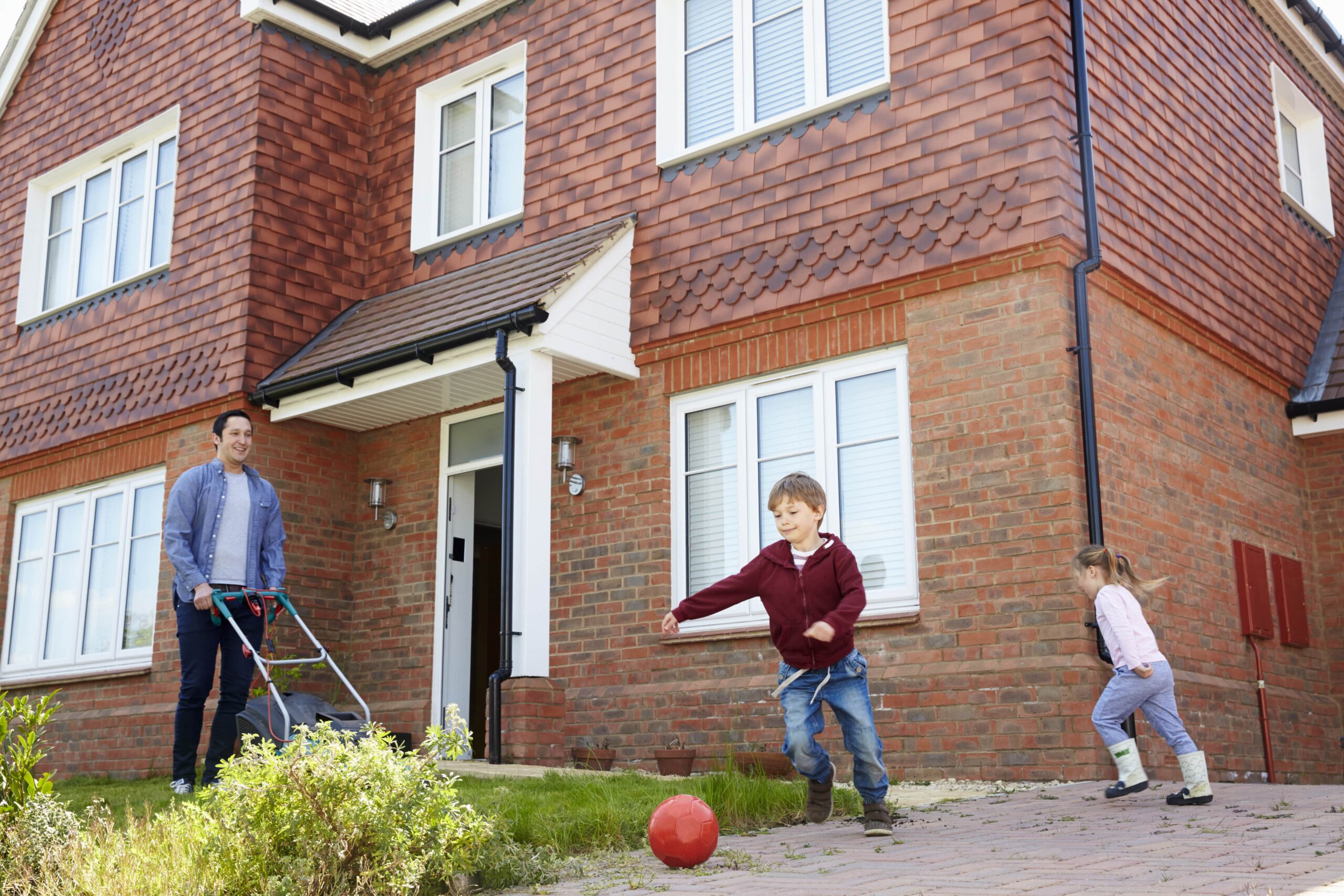 children-play-in-garden-as-father-mows-lawn-outside